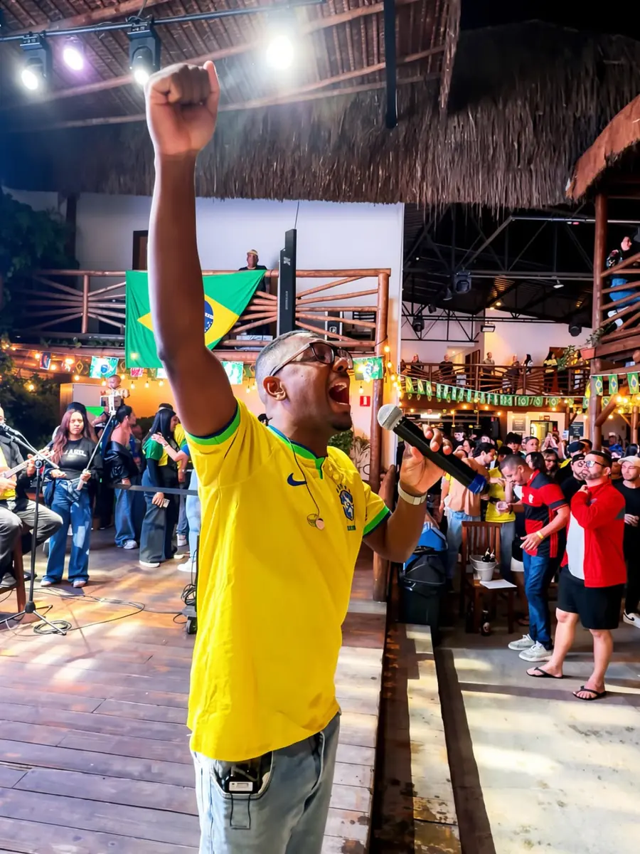 Cantor de punho erguido no palco durante show ao vivo, com o público em volta